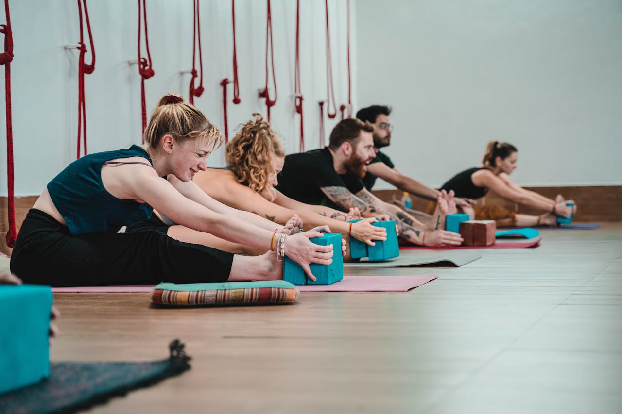 Individuals practicing yoga stretches using blocks in a Rishikesh studio.